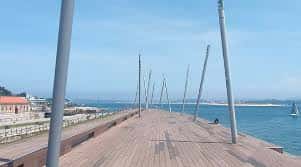 Paseo marítimo con tarima de madera y luminarias modernas junto a la bahía