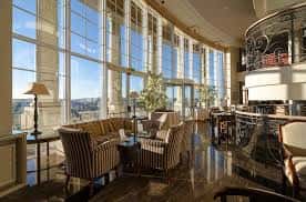 Elegante salón interior con grandes ventanales, techos altos y mobiliario clásico