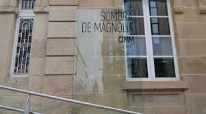 Detalle de la placa de cristal identificativa 'Sombra de Magnolia CIMM' en el exterior del edificio