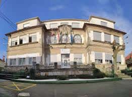 Fachada principal del edificio del CEIP Plurilingüe O Pombal con balcones y banderas
