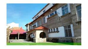 Vista exterior del centro educativo con entrada porticada de piedra y zona de patio