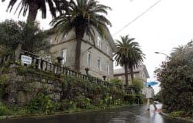 Fachada lateral del centro rodeada de palmeras en un día de lluvia