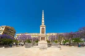 Monumento a Torrijos en el centro de la plaza rodeado de jacarandas en flor