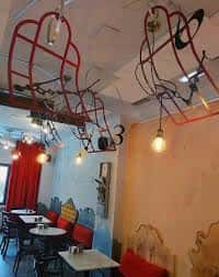 Zona de mesas y asientos con detalles artísticos en el techo y paredes
