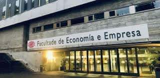 Acceso principal a la facultad con el rótulo identificativo sobre la entrada acristalada