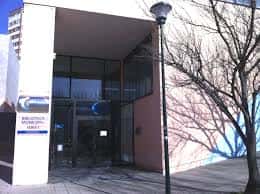 Detalle de la entrada principal acristalada y acceso a la biblioteca municipal