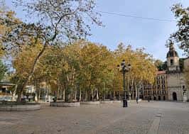 Paseo arbolado en el Parque del Arenal con edificios históricos al fondo