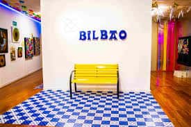 Sala de exposiciones con banco amarillo y decoración temática de Bilbao