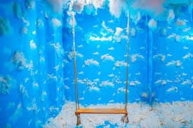 Espacio temático con paredes de nubes azules y un columpio de madera