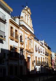 Vista en perspectiva de la fachada exterior y la espadaña de la capilla bajo un cielo despejado