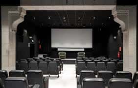 Interior de la sala de proyecciones con pantalla, escenario y patio de butacas
