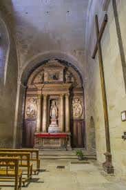Detalle de la capilla interior con retablo clásico y bancos de madera