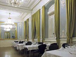 Salón comedor elegante con mesas preparadas para banquetes y ventanales clásicos