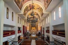 Perspectiva de la nave central con pinturas murales en la bóveda y lámparas ornamentales