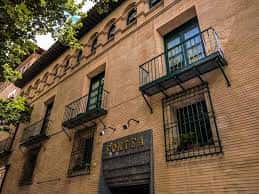 Detalle de la fachada de ladrillo con balcones de forja y arquería superior