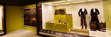 Interior de una sala de exposición con vitrinas que muestran indumentaria y trajes tradicionales