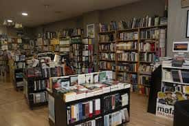 Vista del interior de la librería con estanterías de madera y mesas de novedades