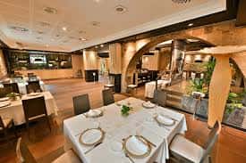 Interior del salón de banquetes con arcos de piedra y mesas preparadas
