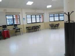 Sala interior polivalente del centro social con mesas, sillas y zona de ordenadores
