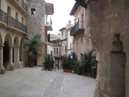 Calle empedrada con arquitectura tradicional y arcos de piedra en el Pueblo Español