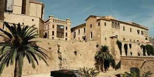 Vista exterior de las murallas y edificios históricos con vegetación mediterránea