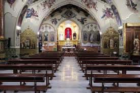 Interior de la iglesia mostrando el altar mayor, las pinturas murales y los bancos