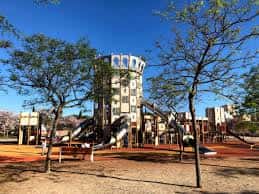 Estructura de juegos infantiles con forma de torre de castillo rodeada de árboles
