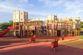 Amplia zona recreativa de madera con puentes y toboganes sobre suelo protector