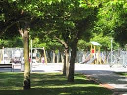 Área de juegos infantiles rodeada de árboles y zonas verdes