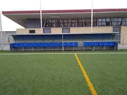 Zona de banquillos con asientos azules en el campo de fútbol de Matalablima