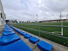 Perspectiva desde la grada con asientos azules hacia el terreno de juego