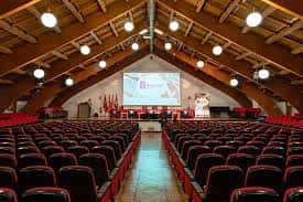 Vista del gran auditorio con filas de butacas rojas y techo con vigas de madera