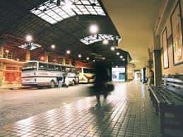 Andén interior con bancos de madera y autobuses estacionados