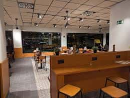 Vista del salón interior con mesas de madera y amplios ventanales