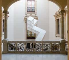 Patio interior con escultura geométrica y ventanales tradicionales