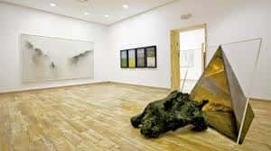 Sala de exposiciones con obras de arte moderno y suelos de madera