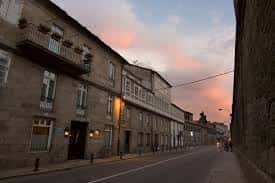 Fachada exterior de piedra del Hotel Virxe da Cerca al atardecer