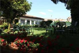 Jardín exterior con mobiliario de forja y flores rojas