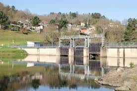 Estructura de la presa del Embalse de Cachamuíña con reflejos en el agua