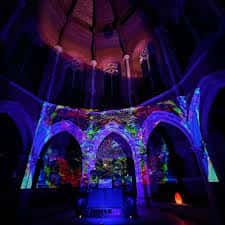 Interior del centro con proyecciones de luces psicodélicas sobre los arcos góticos durante un evento