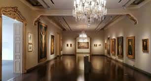 Galería interior del museo con obras de arte expuestas y lámparas de cristal