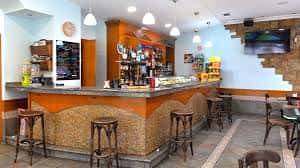 Interior del establecimiento con barra de madera y taburetes
