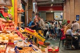 Puesto de productos frescos y visitantes en el interior del Mercado de Triana