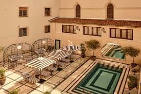 Patio interior con piscina y zona de terraza equipada con sombrillas y mobiliario de descanso