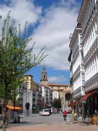 Perspectiva de la plaza con edificios de miradores blancos tradicionales y la torre de la iglesia al fondo