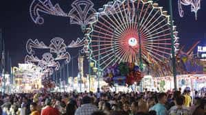 Recinto ferial iluminado por la noche con una gran noria y ambiente festivo
