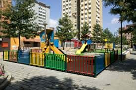 Parque infantil con zona de juegos y columpios rodeado de edificios residenciales