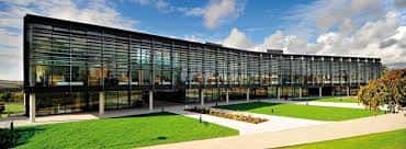 Edificio moderno con fachada acristalada y amplios jardines en el campus