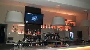 Vista de la barra del bar con estanterías iluminadas y selección de bebidas