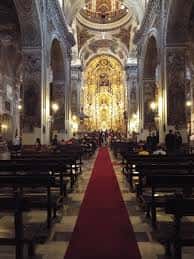 Perspectiva del interior de la iglesia con alfombra roja en el pasillo central hacia el altar mayor